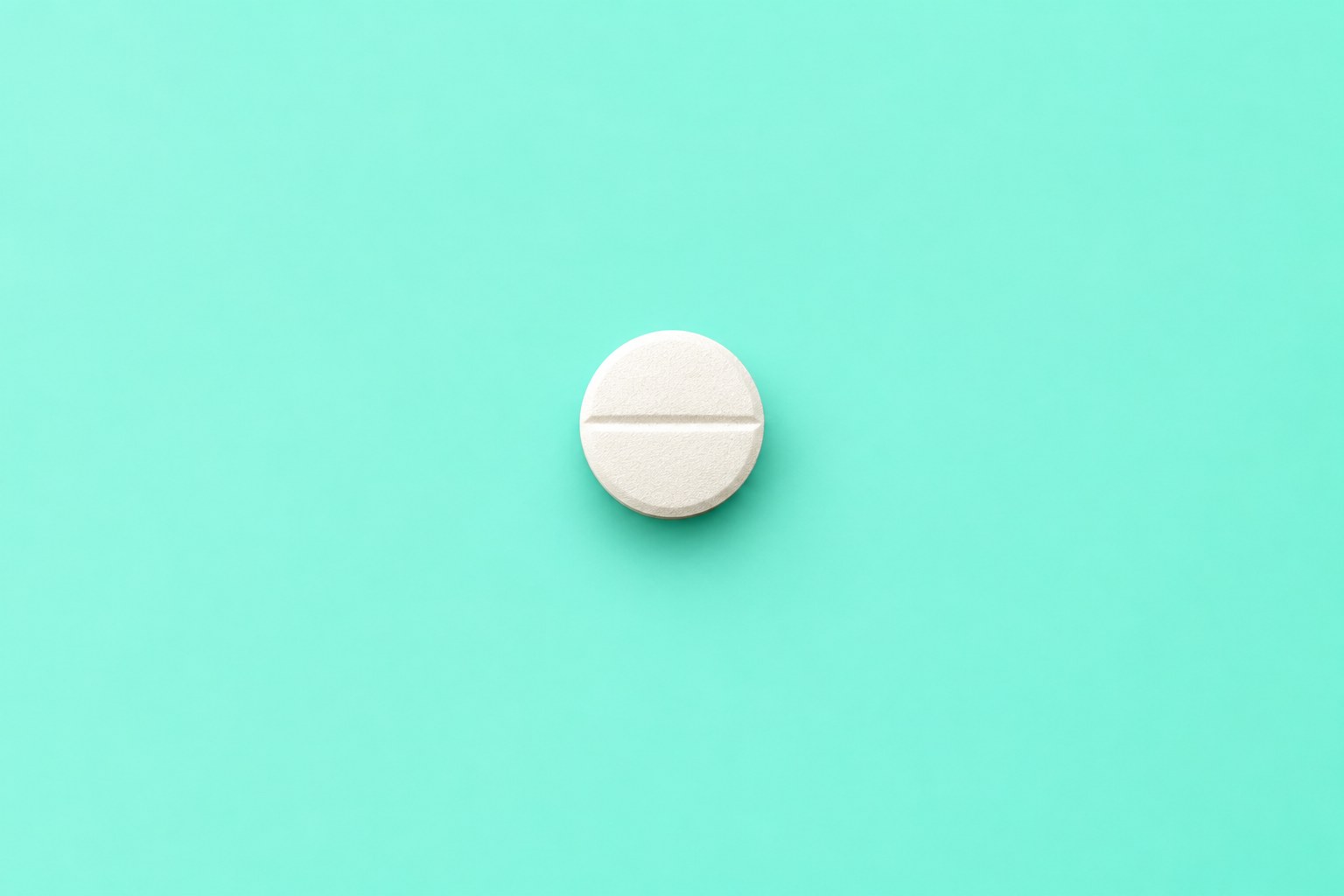 A single white tablet on a teal background, shown for illustration